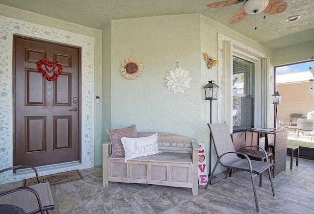 doorway to property featuring covered porch, ceiling fan, and stucco siding