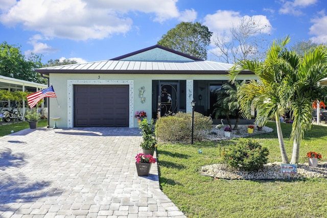 ranch-style home featuring a garage, metal roof, a standing seam roof, decorative driveway, and a front lawn