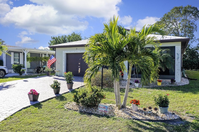 view of front of house with metal roof, decorative driveway, stucco siding, a front lawn, and a standing seam roof