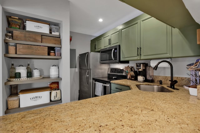 kitchen featuring light stone counters, green cabinetry, stainless steel appliances, and sink