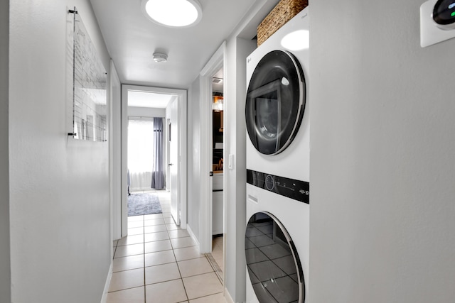 laundry room with stacked washer / dryer and light tile patterned floors