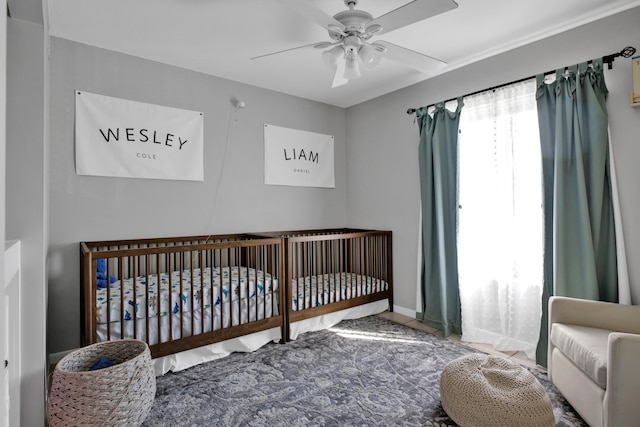 bedroom featuring ceiling fan and a crib