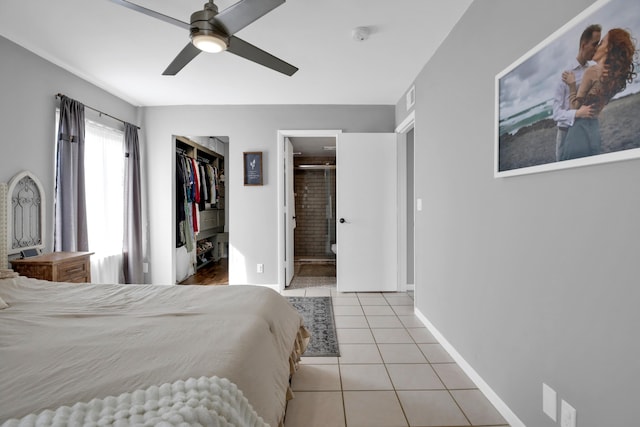 bedroom with ceiling fan, ensuite bathroom, light tile patterned flooring, a walk in closet, and a closet