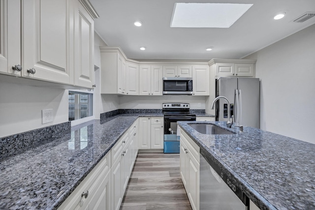 kitchen featuring white cabinetry, appliances with stainless steel finishes, sink, and dark stone counters