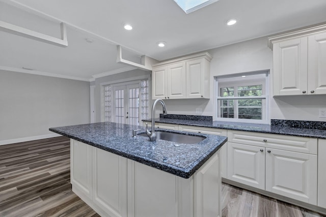 kitchen featuring dark hardwood / wood-style floors, sink, a center island with sink, and white cabinets