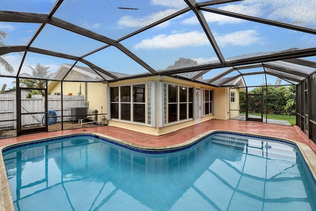 view of pool with cooling unit, a lanai, and a patio area