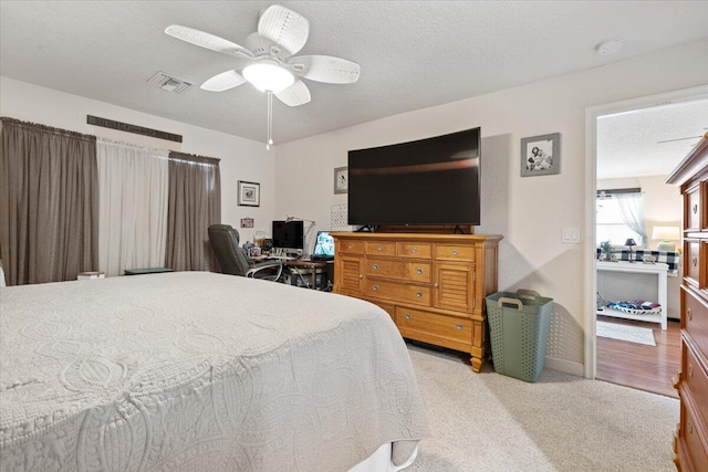 carpeted bedroom featuring ceiling fan and a textured ceiling