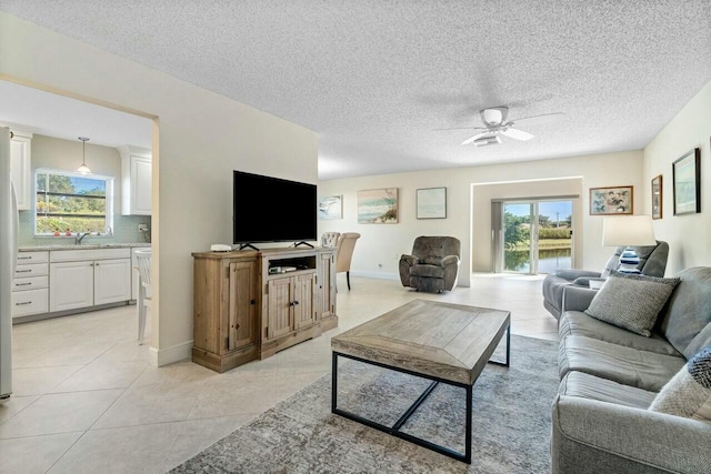 tiled living room with ceiling fan, sink, and a textured ceiling