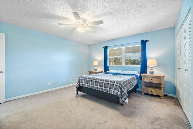 bedroom with ceiling fan, light colored carpet, a closet, and a textured ceiling