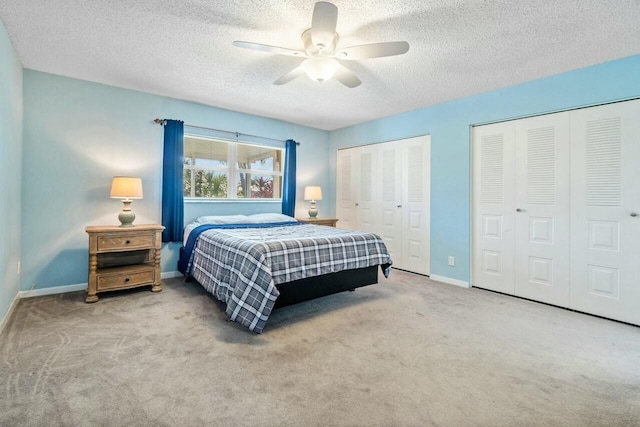 carpeted bedroom featuring ceiling fan, a textured ceiling, and two closets