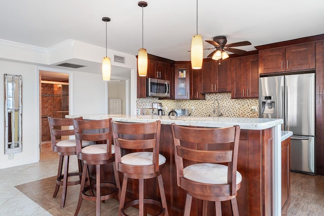 kitchen featuring tasteful backsplash, appliances with stainless steel finishes, pendant lighting, and light stone counters