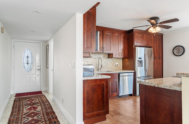 kitchen featuring sink, light stone counters, tasteful backsplash, ceiling fan, and stainless steel appliances