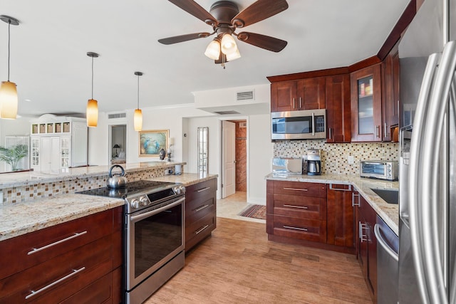 kitchen featuring pendant lighting, appliances with stainless steel finishes, light hardwood / wood-style floors, and decorative backsplash