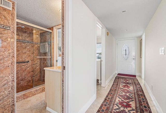 entryway with light tile patterned flooring and a textured ceiling