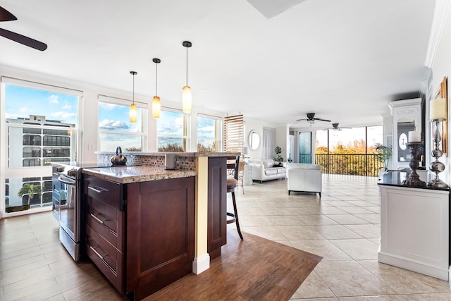 kitchen with a wealth of natural light, stainless steel range with electric stovetop, ceiling fan, and decorative light fixtures