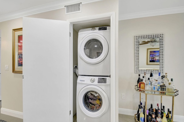 clothes washing area with crown molding and stacked washer / drying machine