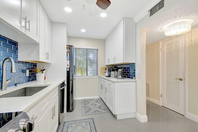 kitchen with sink, light stone counters, black refrigerator, electric stove, and white cabinets