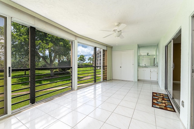 unfurnished sunroom featuring sink and ceiling fan