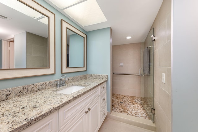 bathroom with walk in shower, vanity, and tile patterned flooring