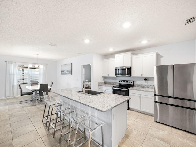 kitchen featuring sink, white cabinetry, appliances with stainless steel finishes, pendant lighting, and a kitchen island with sink