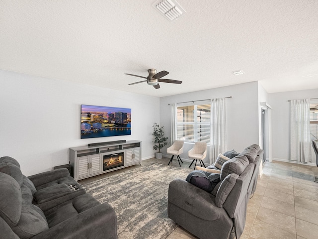 living room with light tile patterned floors, a textured ceiling, a healthy amount of sunlight, and ceiling fan