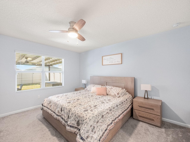 bedroom with ceiling fan, light carpet, and a textured ceiling