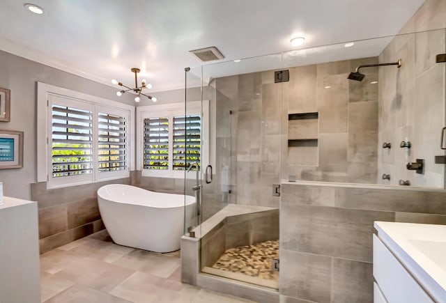 bathroom with vanity, a chandelier, independent shower and bath, and tile walls