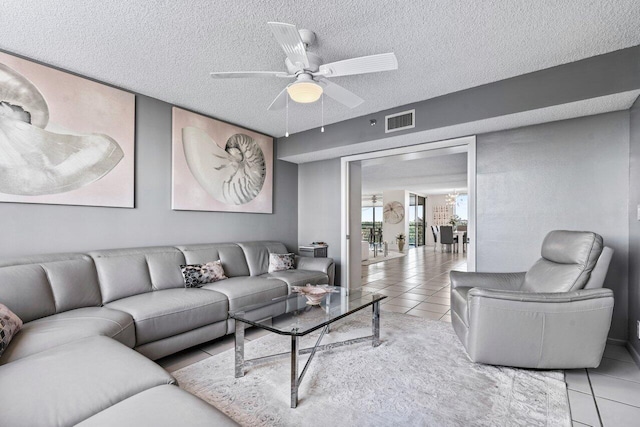 living room with light tile patterned flooring, ceiling fan, and a textured ceiling