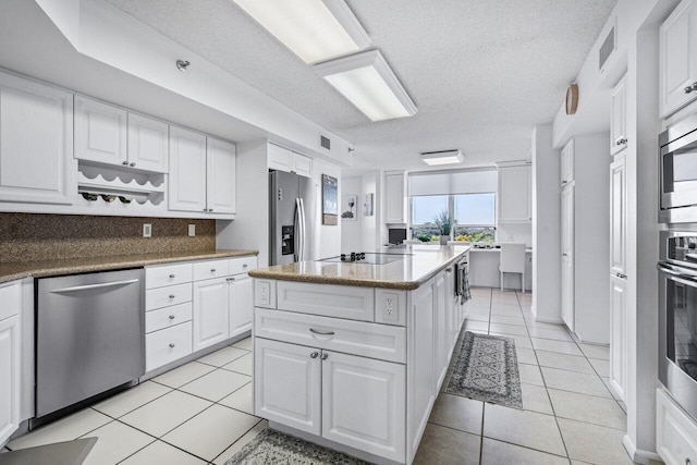 kitchen with white cabinetry, appliances with stainless steel finishes, a center island, and light tile patterned flooring