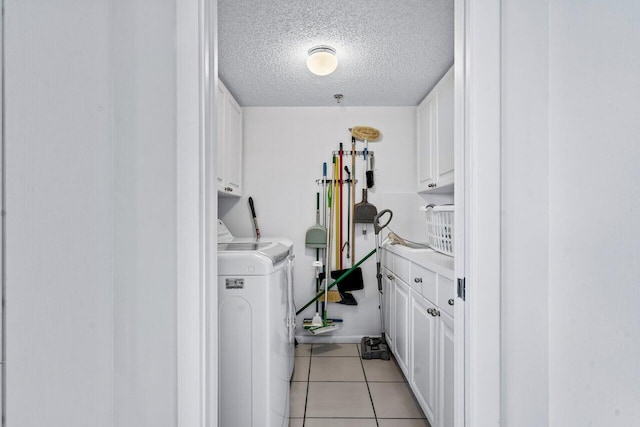 laundry room featuring cabinets, washing machine and dryer, light tile patterned flooring, and a textured ceiling