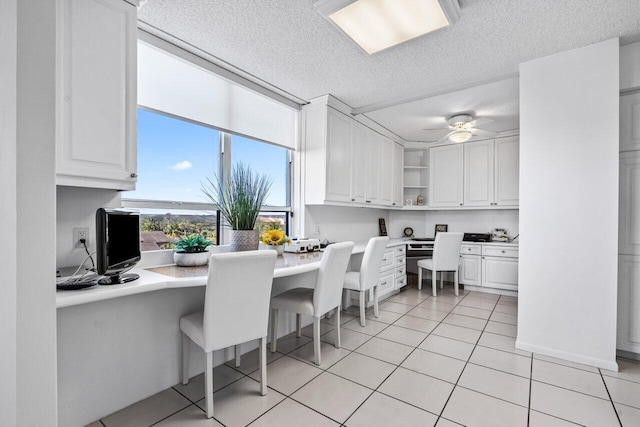 tiled dining area with ceiling fan, built in desk, and a textured ceiling