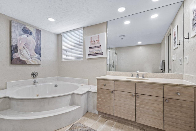 bathroom featuring vanity, a textured ceiling, and a tub to relax in