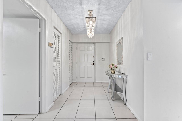 corridor with light tile patterned floors, a chandelier, and a textured ceiling