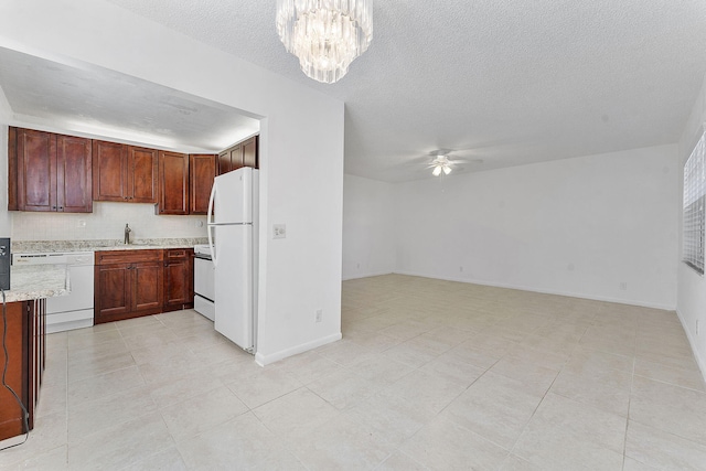 kitchen featuring sink, light stone counters, a textured ceiling, white appliances, and ceiling fan with notable chandelier