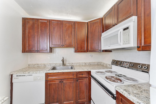 kitchen featuring light stone counters, white appliances, sink, and tasteful backsplash