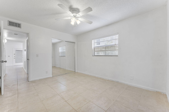 unfurnished bedroom with light tile patterned flooring, ceiling fan, a closet, and a textured ceiling