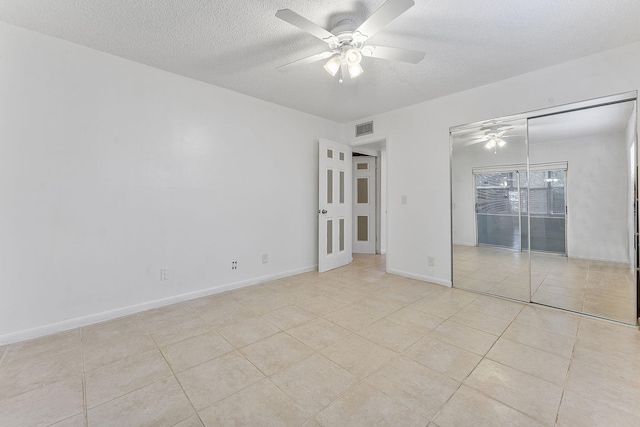 unfurnished bedroom featuring a textured ceiling, a closet, ceiling fan, and light tile patterned flooring