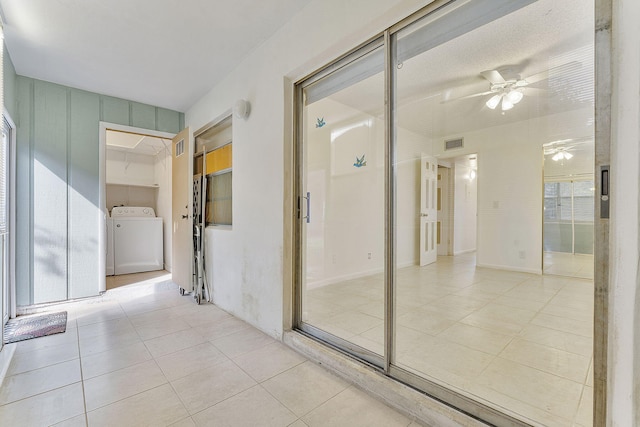 hall featuring washing machine and clothes dryer and light tile patterned flooring