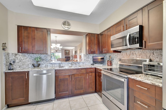 12560 Majesty Cir Unit 401, Boynton Beach, FL 33437 - kitchen featuring appliances with stainless steel finishes, a sink, tasteful backsplash, a chandelier, and light stone counters
