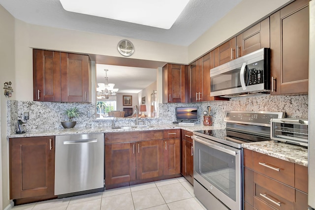 kitchen featuring stainless steel appliances, sink, light stone counters, and decorative backsplash