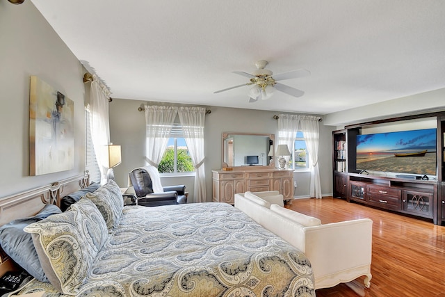 bedroom featuring ceiling fan, multiple windows, and light wood-type flooring