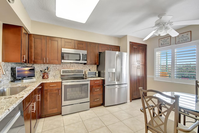 kitchen featuring sink, stainless steel appliances, tasteful backsplash, light stone countertops, and light tile patterned flooring