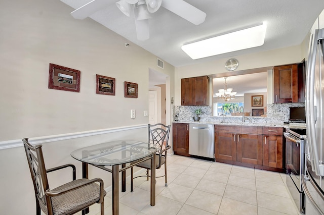 kitchen with sink, ceiling fan with notable chandelier, hanging light fixtures, stainless steel appliances, and decorative backsplash