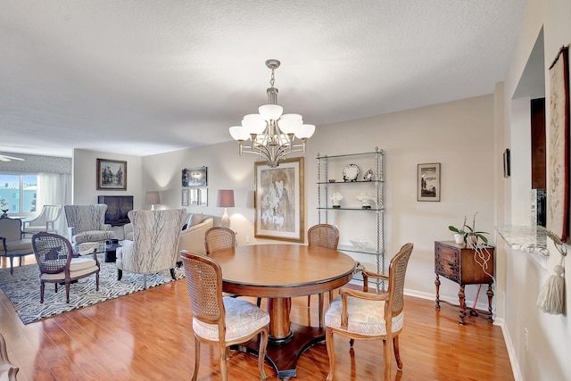 dining space with a textured ceiling, light hardwood / wood-style flooring, and a notable chandelier