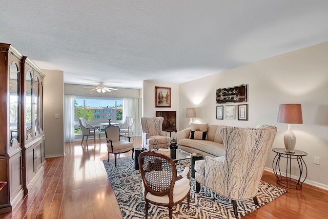 living room featuring hardwood / wood-style flooring, ceiling fan, and a textured ceiling