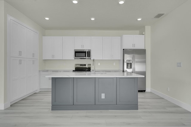 kitchen with an island with sink, white cabinetry, sink, gray cabinetry, and stainless steel appliances