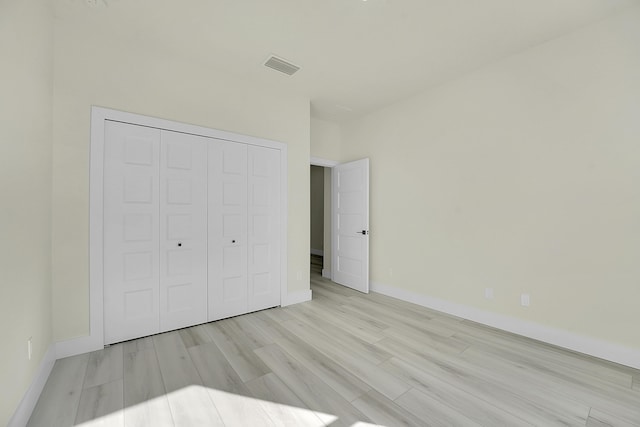 unfurnished bedroom with light hardwood / wood-style flooring and a closet