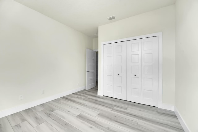 unfurnished bedroom with light hardwood / wood-style flooring and a closet