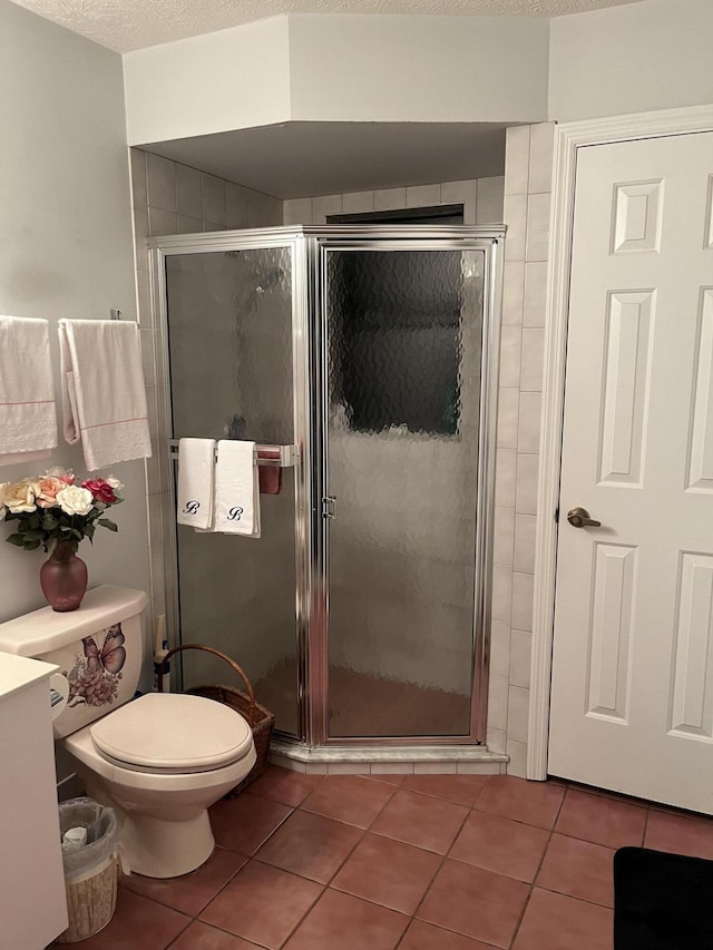 bathroom featuring tile patterned flooring, toilet, a textured ceiling, and a shower with shower door