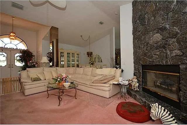 living room with vaulted ceiling, a stone fireplace, carpet, and french doors